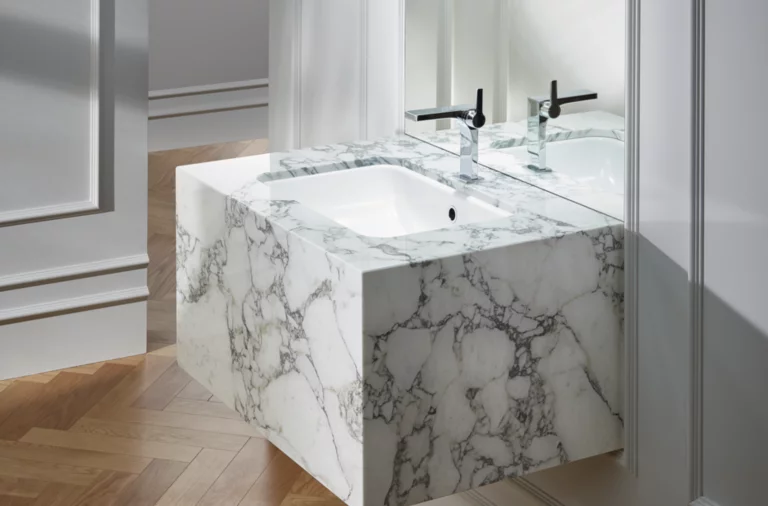 Washbasin on marbled countertop, rectangular shape, with two black faucets, modern bathroom with wooden floor.