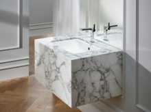 Washbasin on marbled countertop, rectangular shape, with two black faucets, modern bathroom with wooden floor.