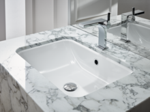 Rectangular steel enamel washbasin in marble-look countertop with modern faucet, accessible design.