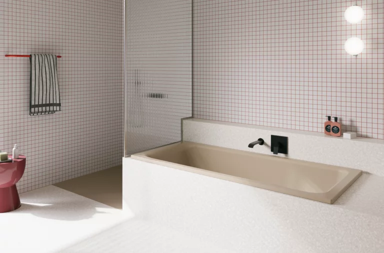 Beigefarbene Badewanne in weiß gefliestem Bad mit Duschbereich, Wandarmatur und rosa Hocker.