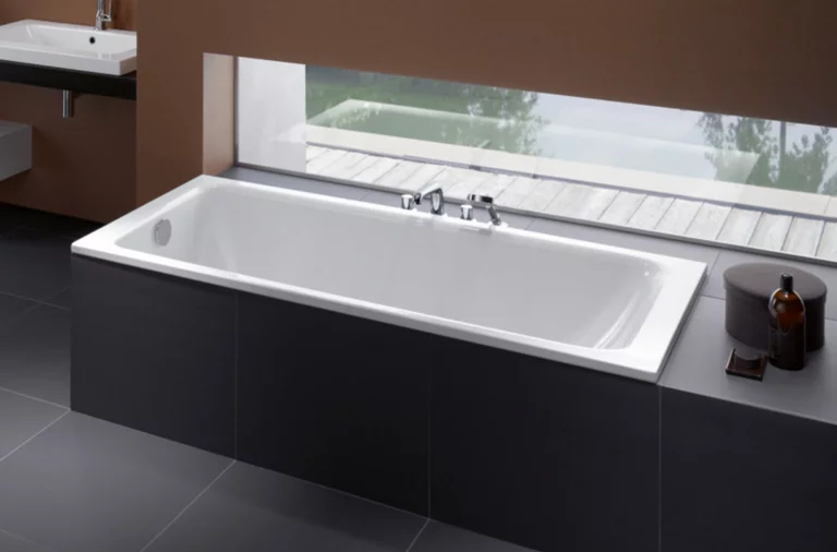 Rechthoekig bad van staal-email, vooraan inbouwplaat met wastafel, moderne badkameruitrusting, groot raam op de achtergrond.