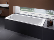 Rechteckige Badewanne aus Stahl-Email, vorne Einbauplatte mit Waschbecken, moderne Badausstattung, großer Fensterbereich im Hintergrund.