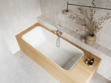 Weiße Badewanne mit gerillter Front in hellem Bad mit Ablage, Handbrause und Vase.