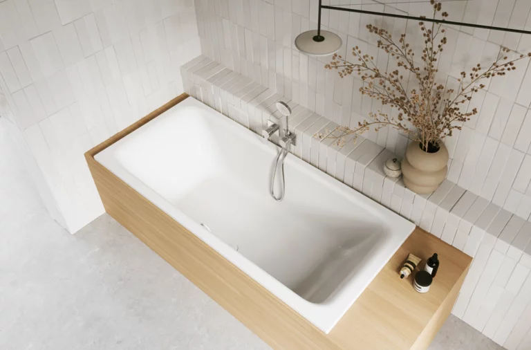Weiße Badewanne in heller Holzoptik-Einfassung mit Handbrause, Ablage und Vase im gefliesten Bad.