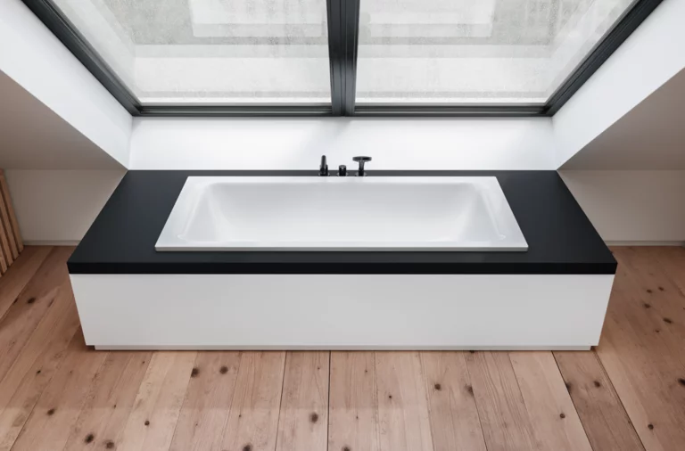 Vasca da bagno rettangolare in acciaio smaltato, integrata in piano nero, sotto grande finestra, ambiente moderno con pavimento in legno.