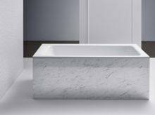 Rectangular steel-enamel bathtub with white marbled paneling in modern bathroom setting.