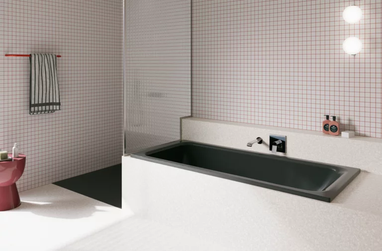 Dunkle Badewanne in hell gefliestem Bad mit Duschbereich, Wandarmatur und rosa Hocker.