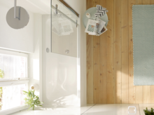 Rectangular steel-enamel bathtub with glass partition in modern bathroom with wood and tile flooring.