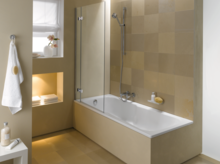 Rechteckige Badewanne aus Stahl-Email mit Duschabtrennung, beige gefliestes Badezimmer, Handbrause, Handtuch, Ablagenische.