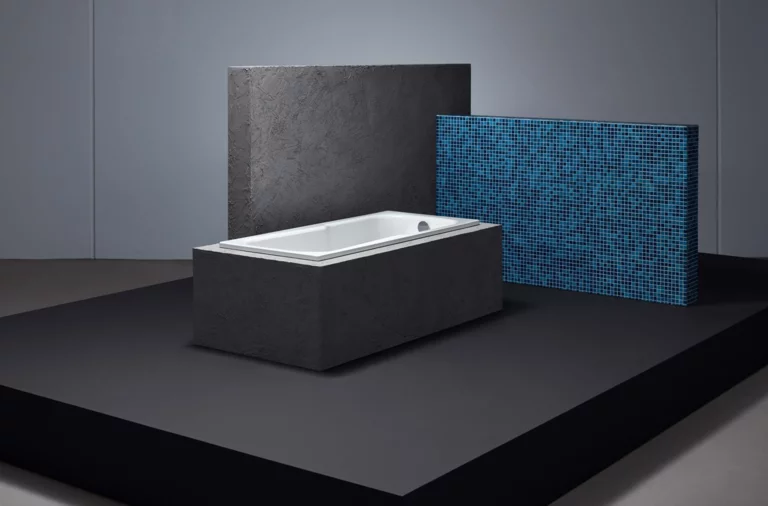 Baignoire rectangulaire en acier émaillé aux bords droits, au design moderne, posée sur une plateforme noire devant des panneaux muraux.