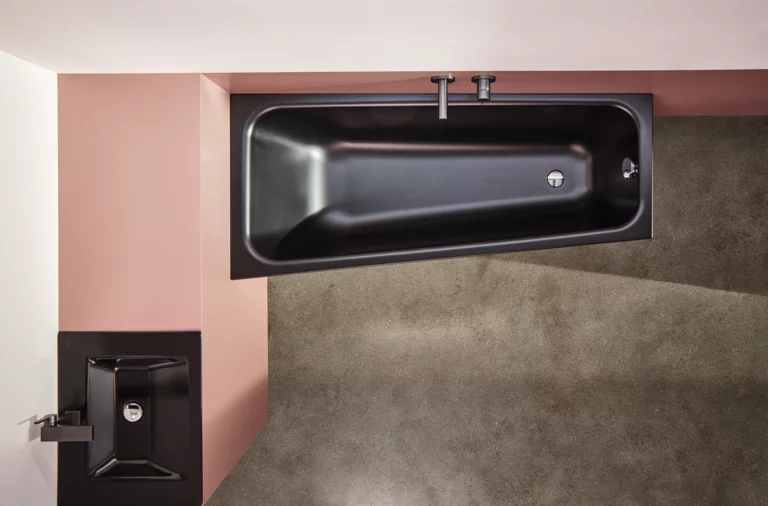 Vasca da bagno rettangolare nera in acciaio smaltato e lavabo squadrato su piano d’appoggio, vista moderna del bagno dall’alto.