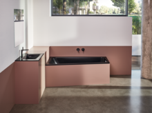 Vasca da bagno rettangolare in acciaio smaltato nera e lavabo su piano d’appoggio in moderno bagno accessibile con finestra.