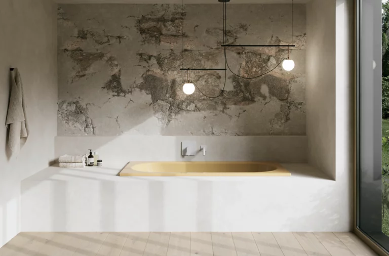 Gelbe Badewanne in hellem Bad mit weißer Einfassung, strukturierter Wand, Pendelleuchten und großem Fenster.