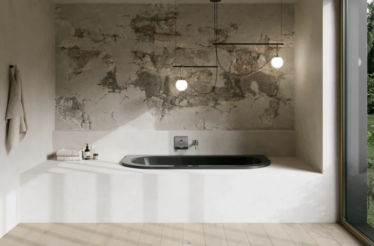 Donker bad in lichte badkamer met witte ombouw, gestructureerde wand, hanglampen en groot raam.