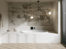 Wit bad in lichte badkamer met witte ombouw, gestructureerde wand, hanglampen en groot raam.