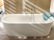 Freistehende, ovale Badewanne aus Stahl-Email vor Wand, Handtuch am Rand, moderne Armaturen.