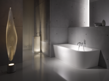 Freistehende, rechteckig-gerundete Badewanne aus Stahl-Email in modernem Bad mit minimalistischer Einrichtung und stehendem Design-Leuchtobjekt.