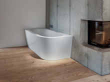 Freistehende, rechteckige Badewanne aus Stahl-Email mit abgerundeter Vorderseite in modernem Badezimmer mit Kamin.