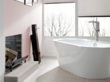 现代浴室中独立椭圆形钢瓷浴缸，木纹瓷砖，大量自然光