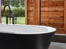 独立椭圆形钢瓷浴缸，哑黑外侧，置于木墙前。