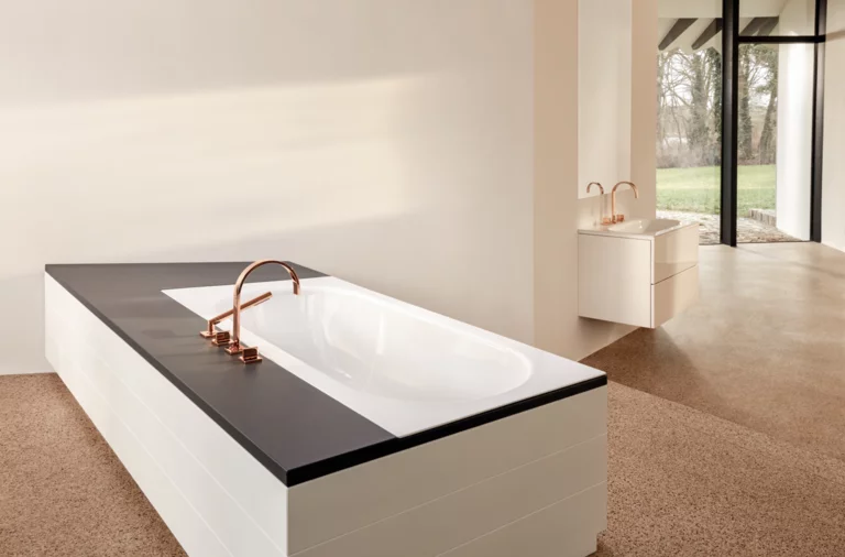 Rechteckige Stahl-Email-Badewanne mit schwarzer Umrandung, im Hintergrund Waschbecken auf weißer Einbauplatte, moderne Armaturen.