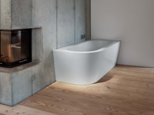 Freistehende, rechteckige Badewanne aus Stahl-Email mit abgerundeter Vorderseite in modernem Badezimmer mit Kamin.