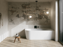 Weiße freistehende Badewanne in hellem Bad mit Natursteinoptik-Wand, Hocker, Handtuch und großem Fenster.
