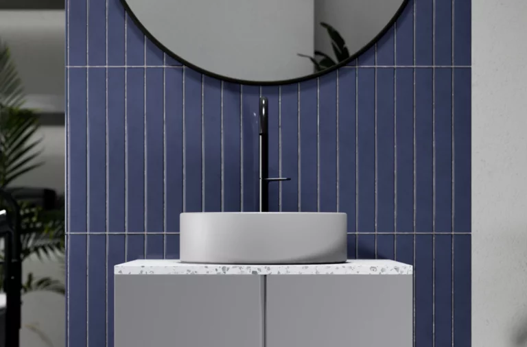 Rundes Waschbecken auf rechteckiger Einbauplatte vor blauer Fliesenwand, modernes Design, sichtbarer Wasserhahn.