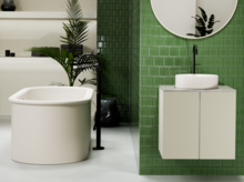 Runde Stahl-Email-Badewanne und rundes Waschbecken auf Einbauplatte, modernes Bad mit grünen Wandfliesen.