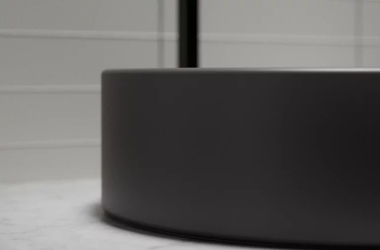 Rundes Stahl-Email Waschbecken auf Einbauplatte, matte Oberfläche, modernes Design, seitliche Detailaufnahme.