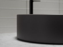 Rundes Stahl-Email Waschbecken auf Einbauplatte, matte Oberfläche, modernes Design, seitliche Detailaufnahme.