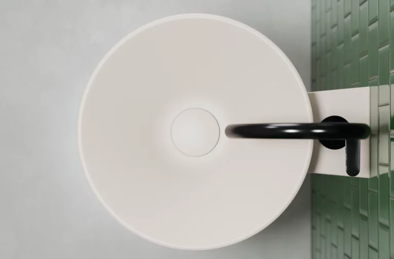 圆形搪瓷钢洗手盆配黑色龙头，安装在绿色瓷砖墙上。