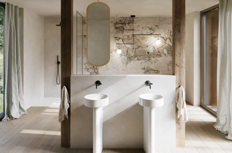 Lichte badkamer met twee witte vrijstaande wastafels, wandkranen en een grote spiegel voor een stenen wand.