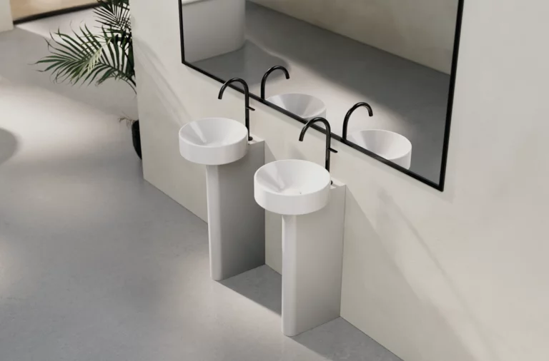 两个带高底座的钢瓷圆形洗手盆，镜子前，现代极简浴室设计。