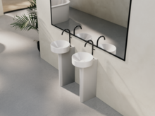 两个带高底座的钢瓷圆形洗手盆，镜子前，现代极简浴室设计。