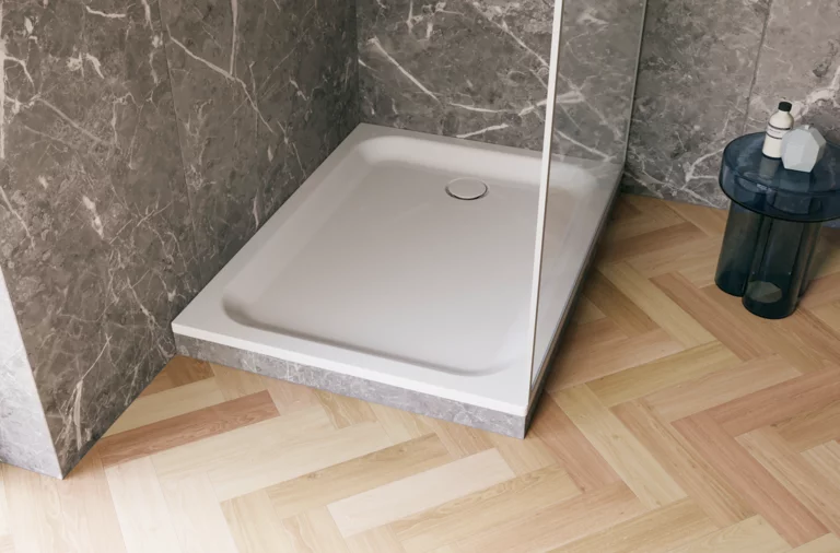 Weiße, bodengleiche Duschwanne in einer modernen Dusche mit grauer Marmoroptik und hellem Fischgrät-Holzboden.