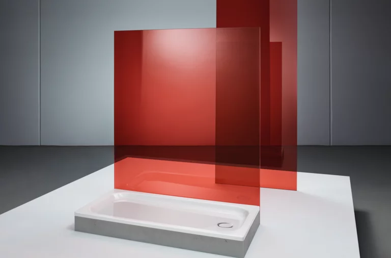 Rechteckige Duschwanne aus Stahl-Email mit flacher Form, daneben rote Glasabtrennung, modernes minimalistisches Design.