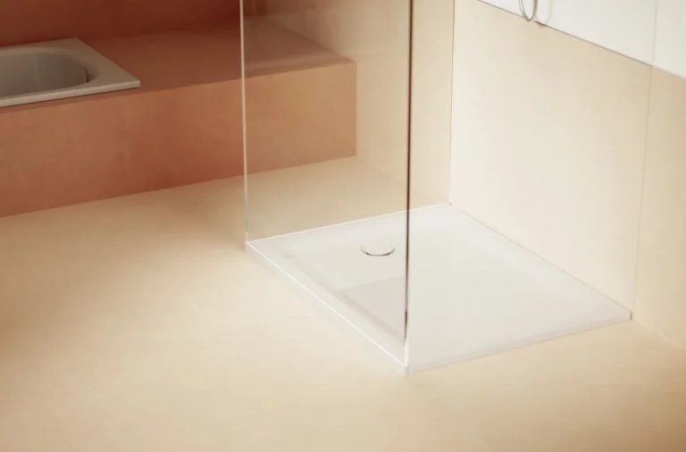 Helles Bad mit weißer, quadratischer Duschwanne, Glasabtrennung und eingebauter Badewanne im Hintergrund.