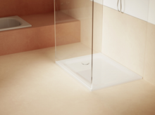 Helles Bad mit weißer, quadratischer Duschwanne, Glasabtrennung und eingebauter Badewanne im Hintergrund.