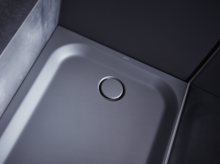 Square steel enamel shower tray with rounded corners and central drain, in a modern bathroom design.