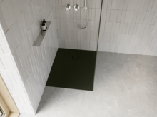 Dunkle, bodengleiche Duschwanne in moderner Dusche mit weißen Fliesen, Glasabtrennung, silberner Armatur und grauem Boden.
