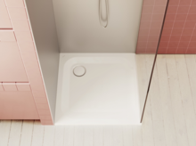 白色方形淋浴底座，配墙装装置，周围为粉色瓷砖和浅色木地板。