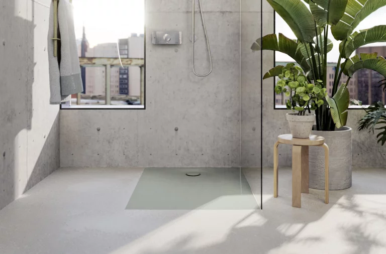 Piatto doccia rettangolare in acciaio smaltato, a filo pavimento, in bagno moderno con parete in cemento e grandi piante.