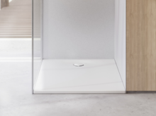 Doccia minimal con piatto bianco, parete in vetro e design luminoso in un bagno moderno.