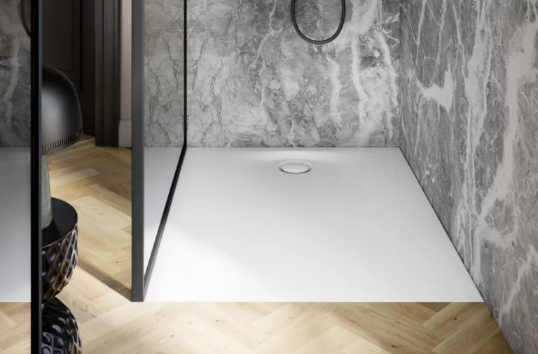 Moderne Dusche mit weißer Duschwanne, grauem Marmorwandbelag und Glasabtrennung auf hellem Holzfußboden.