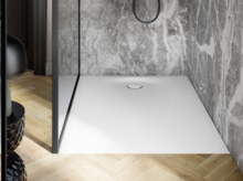 Moderne Dusche mit weißer Duschwanne, grauem Marmorwandbelag und Glasabtrennung auf hellem Holzfußboden.