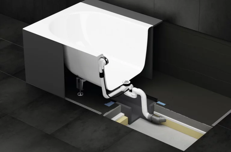 Badkuip met deels zichtbare onderbouw en installatiebox voor afvoeraansluiting onder de tegelvloer.