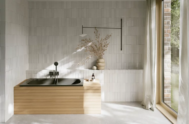 Helles Bad mit dunkel eingelassener Badewanne, heller Front, Fliesenwand, bodentiefem Fenster und Vorhang.