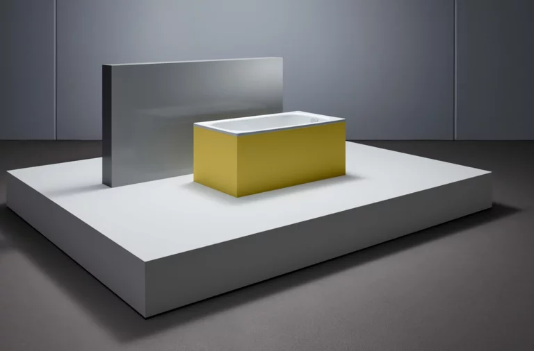 Rectangular steel-enamel bathtub with yellow cladding, on white pedestal in modern room.