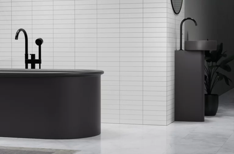 Oval-shaped steel-enamel bathtub and round washbasin on countertop in front of light wall, modern bathroom design.